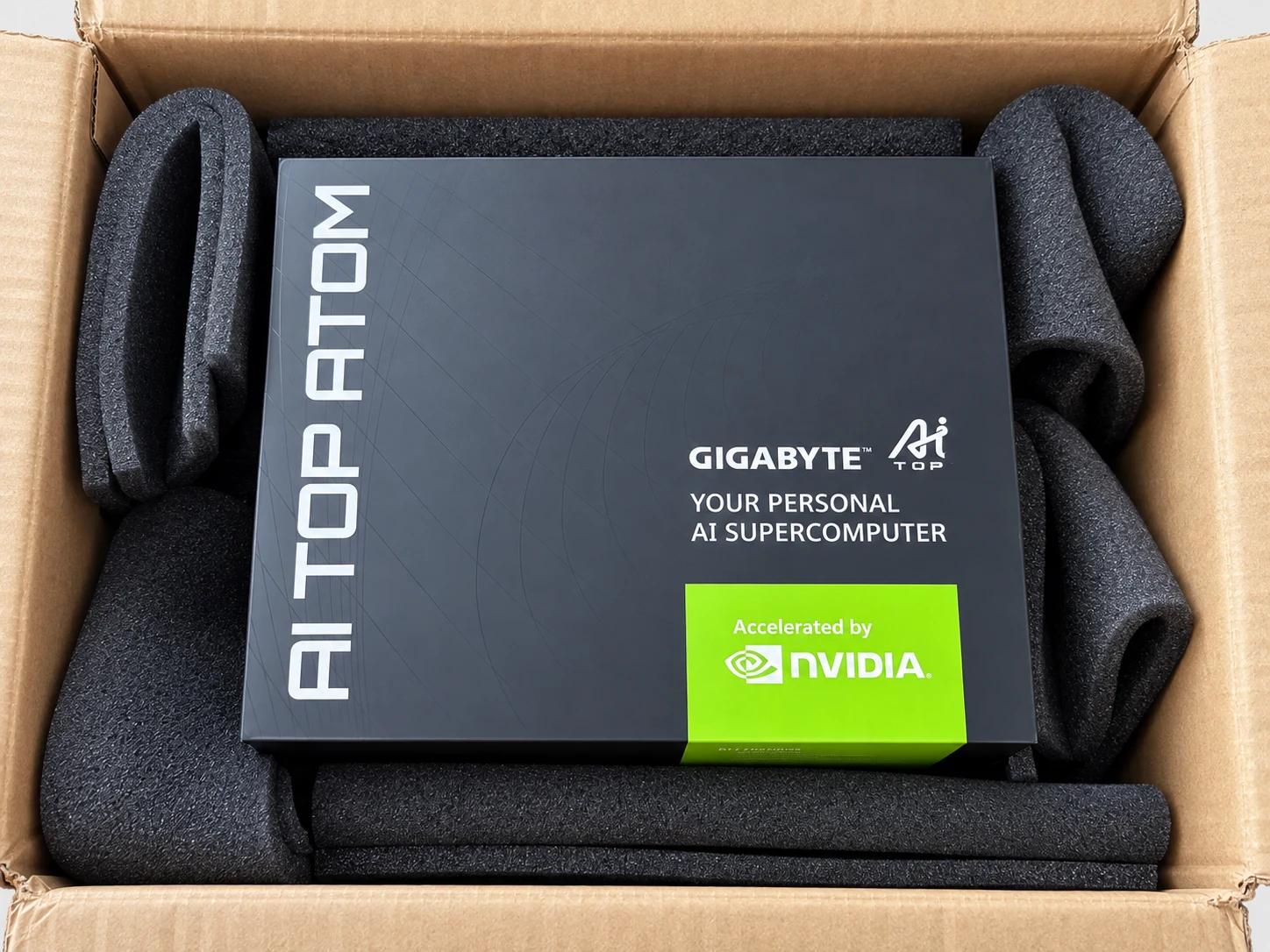Boîte noire de l'AI TOP ATOM dans son carton d'expédition, calée par de la mousse, avec les mentions GIGABYTE AI TOP et Accelerated by NVIDIA.