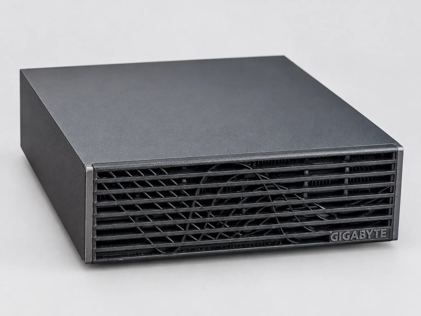L'AI TOP ATOM de GIGABYTE vue de trois quarts côté droit, posée à plat : capot gris anthracite et façade à lamelles noires.